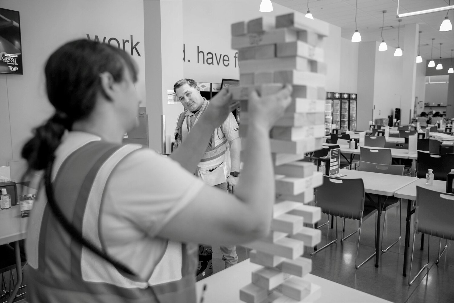 STACKING EXPERTISE: He seems skeptical of Tiffany Ruby's choice of a block as the two share a tense game of giant Jenga in the Amazon breakroom.